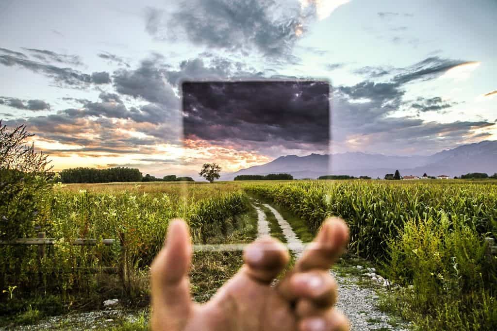 Image of outdoors blurry with a hand holding a filter to show clear sky